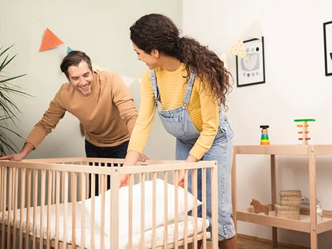 Prepárate para la llegada de tu bebé con nuestra guía completa Un hombre y una mujer preparan la cuna del bebé